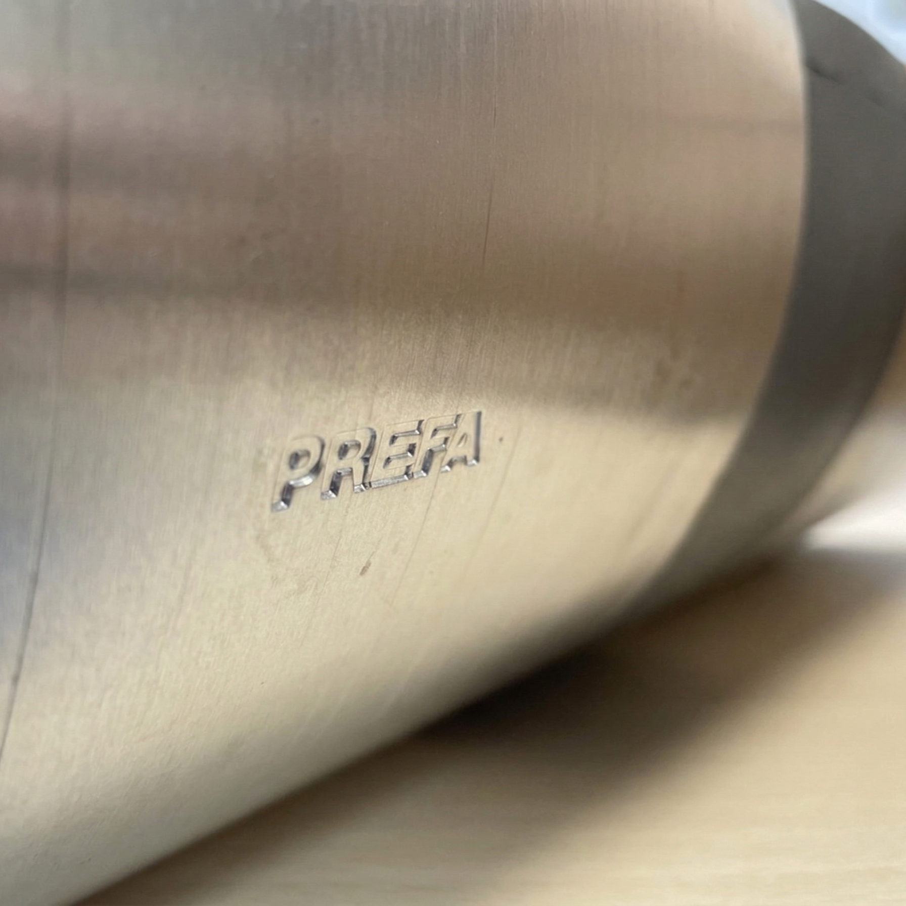 Ein PREFA R-Rinnendila-Set für Dachrinnen der Nenngröße 333 (RG333). Das Bild zeigt das Dehnungsausgleichselement aus Aluminium mit einer schwarzen P.10 Oberfläche und einem silbernen Metallkern neben der originalen braunen Kartonverpackung der Marke PREFA.